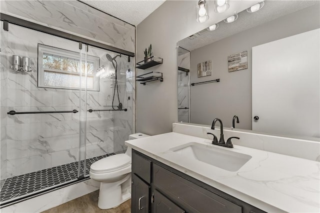 bathroom featuring a marble finish shower, toilet, vanity, wood finished floors, and a textured ceiling