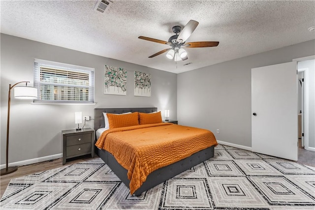 bedroom featuring a ceiling fan, baseboards, visible vents, and a textured ceiling