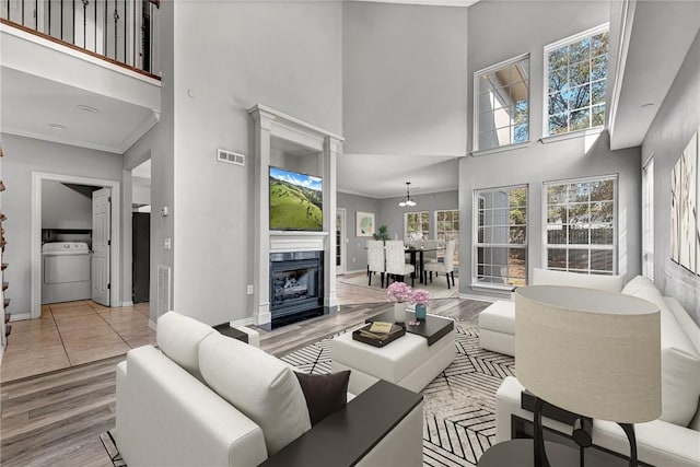 living room featuring washer / clothes dryer, a premium fireplace, and a high ceiling