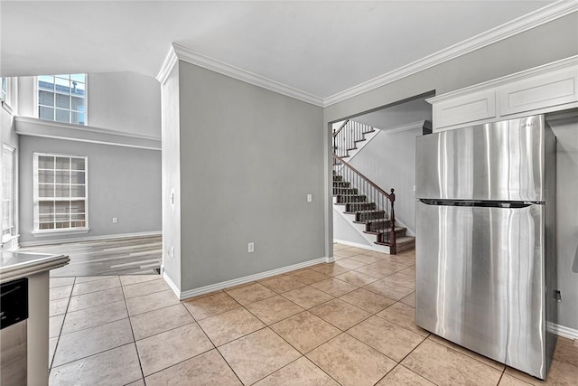 kitchen with stainless steel refrigerator, white cabinetry, ornamental molding, and light tile patterned floors