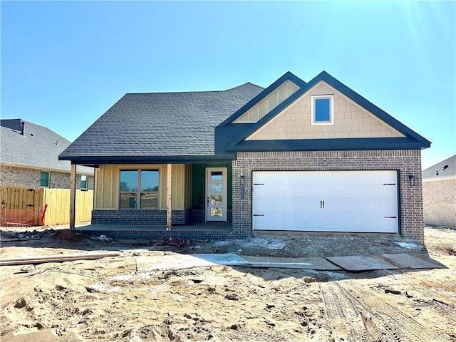 view of front of house with a porch, fence, board and batten siding, an attached garage, and brick siding