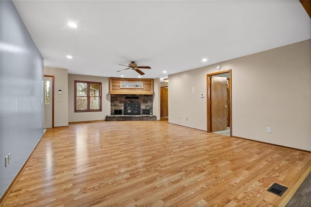 unfurnished living room with ceiling fan, a fireplace, and light hardwood / wood-style floors