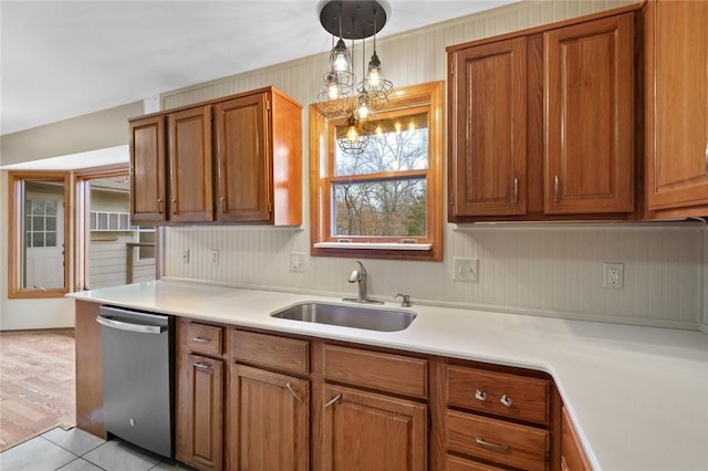 kitchen with dishwasher, sink, light tile patterned floors, and decorative light fixtures