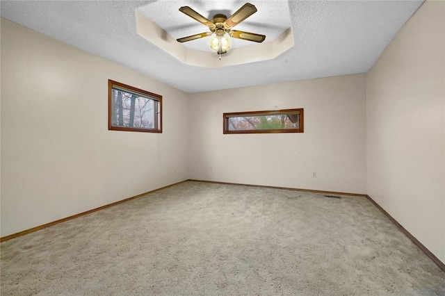 unfurnished room featuring ceiling fan, carpet, a textured ceiling, and a tray ceiling