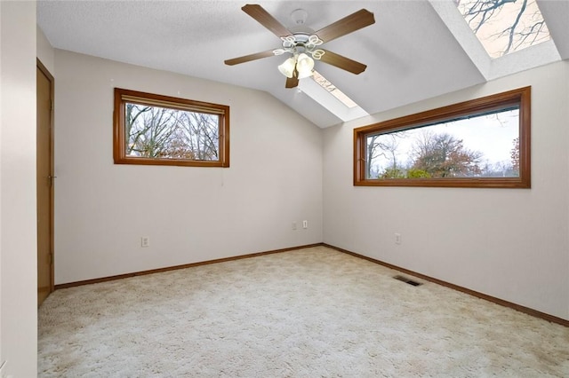 interior space with vaulted ceiling with skylight, plenty of natural light, light carpet, and a textured ceiling