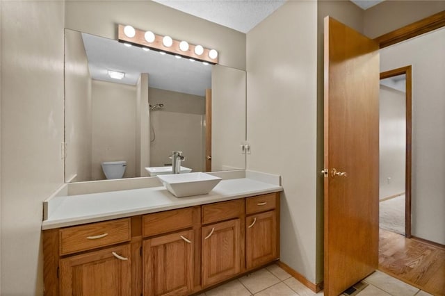 bathroom featuring vanity, tile patterned flooring, a shower, and toilet