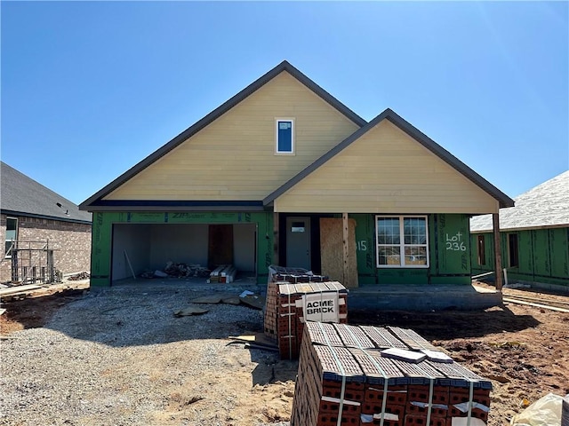 unfinished property with a porch, driveway, and a garage