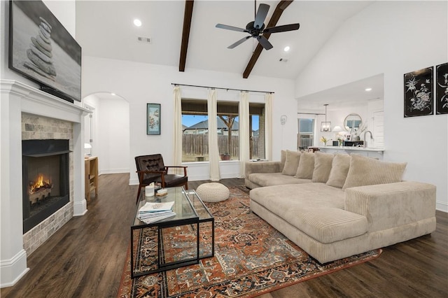 living room with dark hardwood / wood-style flooring, beam ceiling, high vaulted ceiling, and ceiling fan