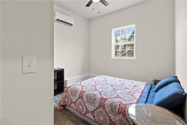 bedroom featuring hardwood / wood-style floors, a wall mounted air conditioner, and ceiling fan