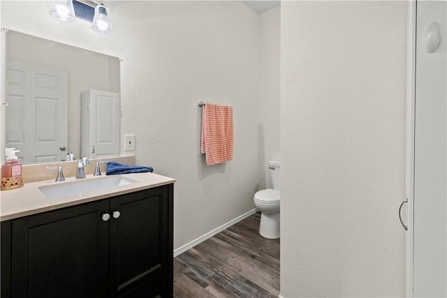 bathroom featuring wood-type flooring, toilet, and vanity