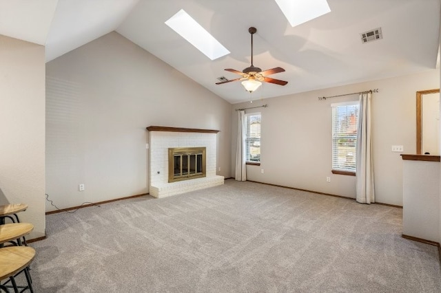 unfurnished living room featuring lofted ceiling with skylight, a brick fireplace, light colored carpet, and ceiling fan