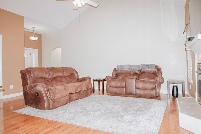 living room featuring high vaulted ceiling, a fireplace, and light hardwood / wood-style flooring