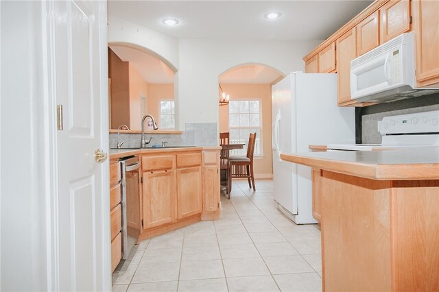 kitchen featuring sink, backsplash, light tile patterned floors, light brown cabinets, and white appliances