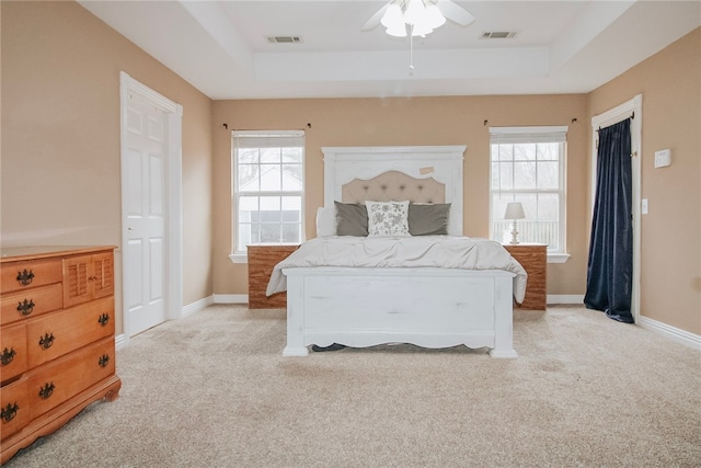 carpeted bedroom with ceiling fan and a tray ceiling