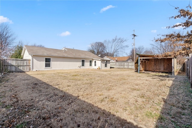 back of house with a fenced backyard and a yard