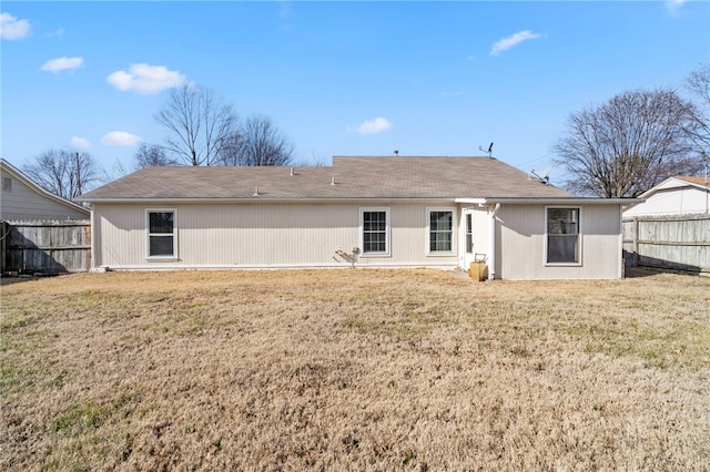 back of property featuring fence and a lawn