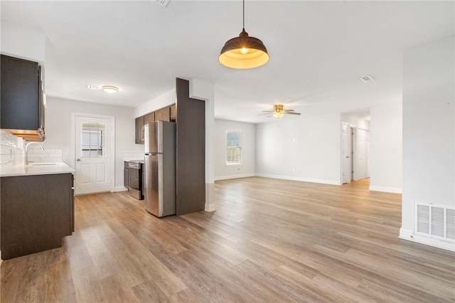 kitchen featuring stainless steel appliances, light countertops, visible vents, open floor plan, and a sink