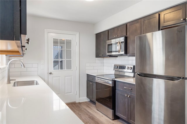 kitchen featuring light countertops, appliances with stainless steel finishes, a sink, and dark brown cabinets