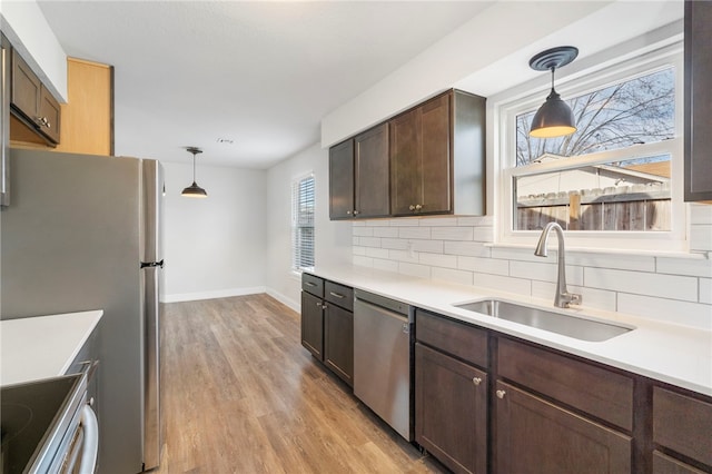 kitchen featuring appliances with stainless steel finishes, pendant lighting, light countertops, and a sink