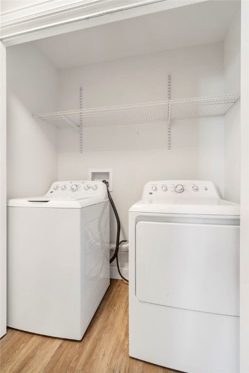 washroom with laundry area, washer and clothes dryer, and wood finished floors