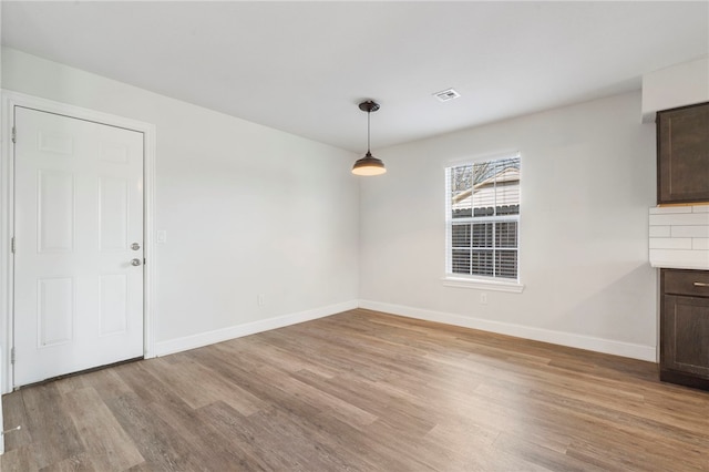 unfurnished dining area with light wood-style flooring, visible vents, and baseboards