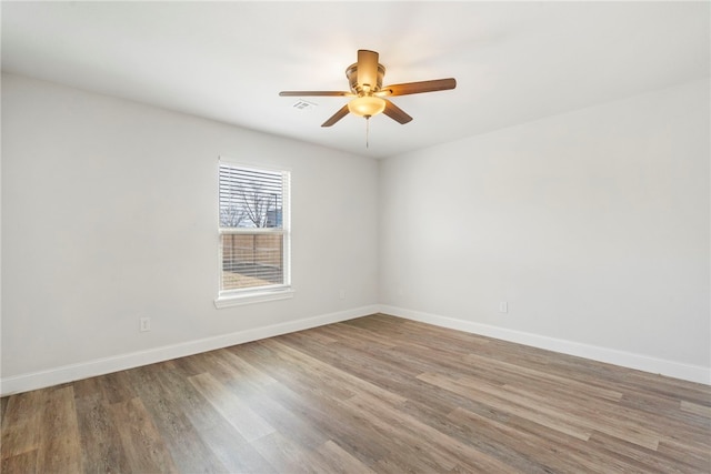 empty room with visible vents, ceiling fan, baseboards, and wood finished floors