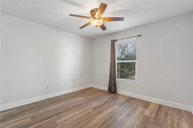 spare room featuring light wood-type flooring, ceiling fan, and baseboards