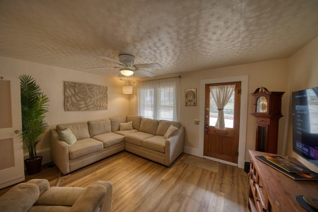 living room with ceiling fan, light hardwood / wood-style flooring, and a textured ceiling