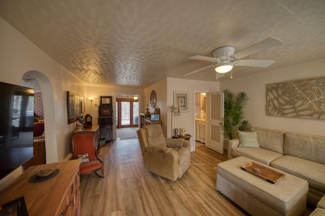 living room featuring ceiling fan, light hardwood / wood-style flooring, and a textured ceiling