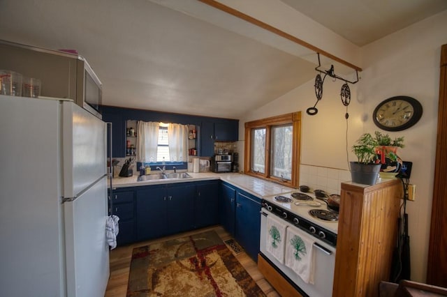 kitchen featuring sink, white appliances, blue cabinetry, decorative backsplash, and vaulted ceiling