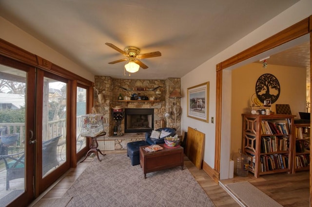 living area featuring ceiling fan, a fireplace, and light hardwood / wood-style floors