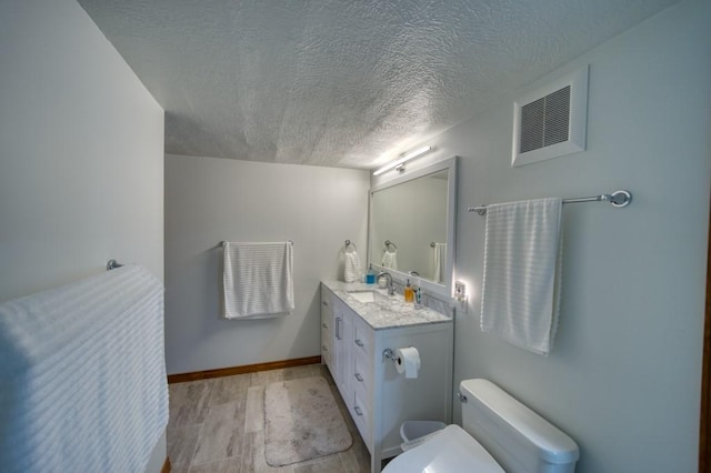 bathroom with vanity, hardwood / wood-style floors, toilet, and a textured ceiling