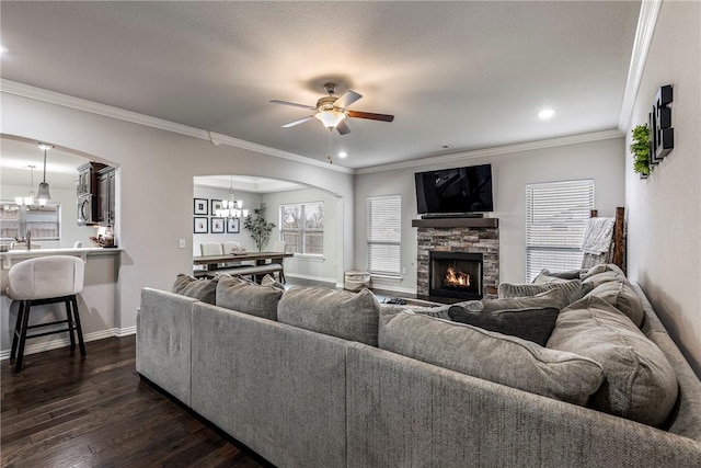 living room with sink, crown molding, dark hardwood / wood-style floors, a fireplace, and ceiling fan with notable chandelier