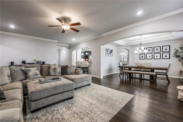 living room with ornamental molding, dark hardwood / wood-style flooring, a raised ceiling, and ceiling fan with notable chandelier