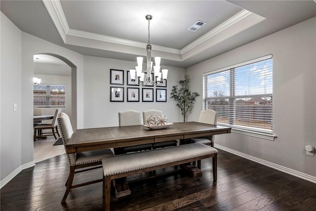 dining space featuring a tray ceiling, ornamental molding, and dark hardwood / wood-style floors