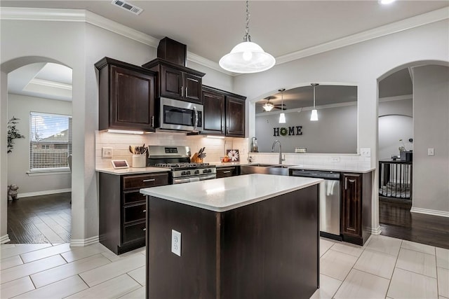 kitchen with sink, crown molding, a kitchen island, pendant lighting, and stainless steel appliances