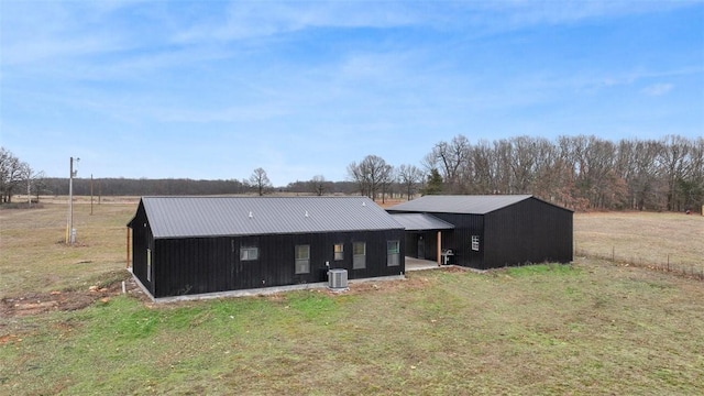 back of property featuring central AC and a lawn