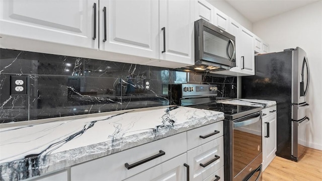 kitchen with light stone counters, stainless steel range with electric stovetop, light wood-type flooring, and white cabinets