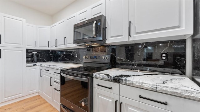 kitchen featuring white cabinetry, stainless steel appliances, and light stone counters