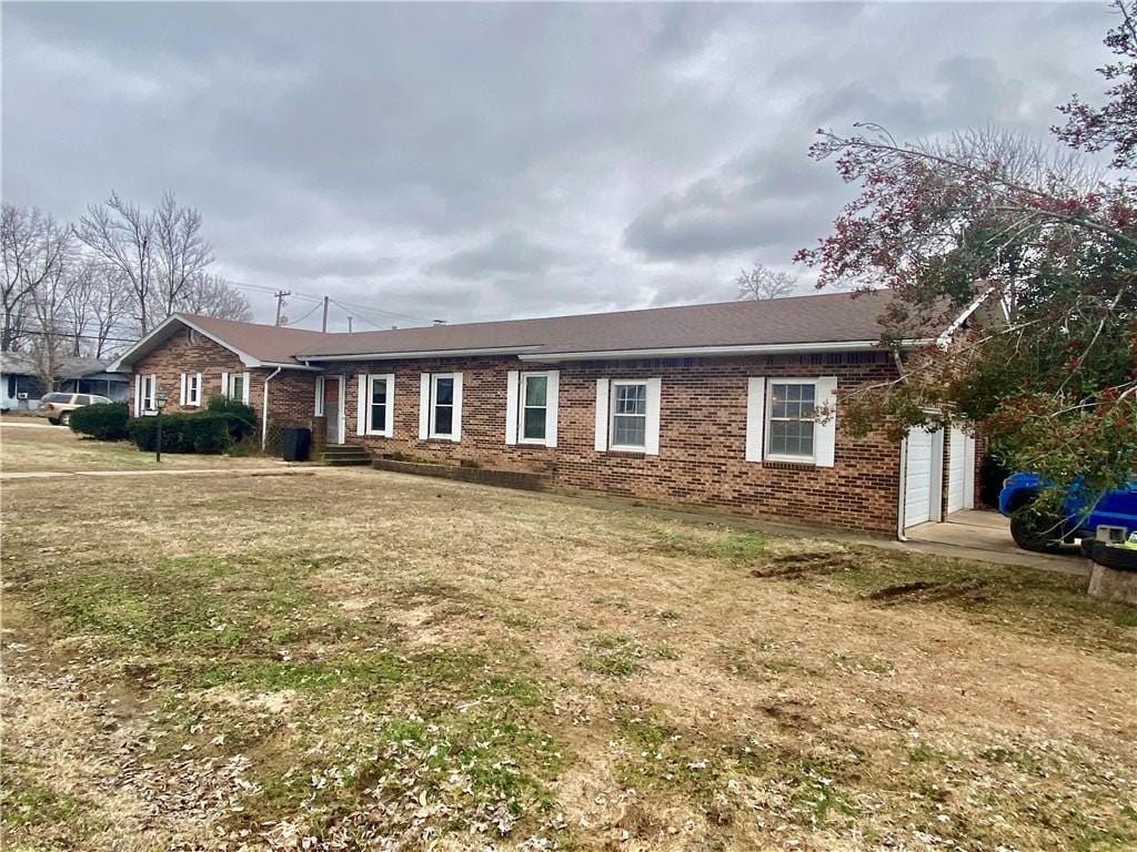 single story home with a garage and a front lawn