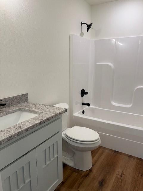 full bathroom with wood-type flooring, tub / shower combination, vanity, and toilet