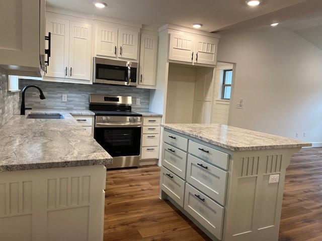 kitchen with light stone counters, appliances with stainless steel finishes, and a kitchen island