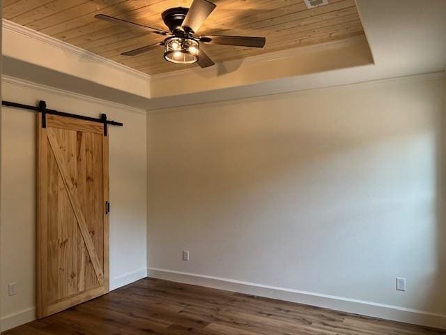 spare room featuring ornamental molding, a tray ceiling, a barn door, dark wood-type flooring, and wooden ceiling