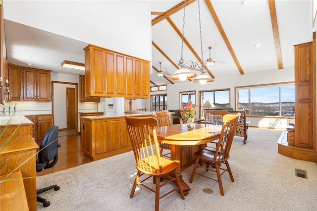 dining space featuring a wealth of natural light, beam ceiling, and light colored carpet