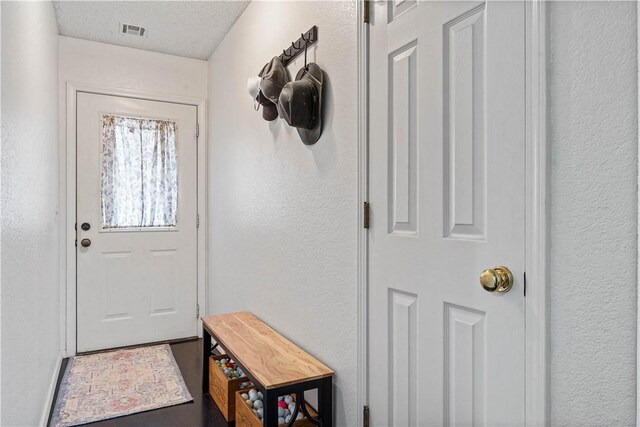 doorway to outside with a textured ceiling