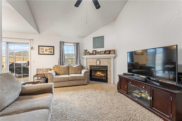 carpeted living room with a tile fireplace, vaulted ceiling, and a textured ceiling