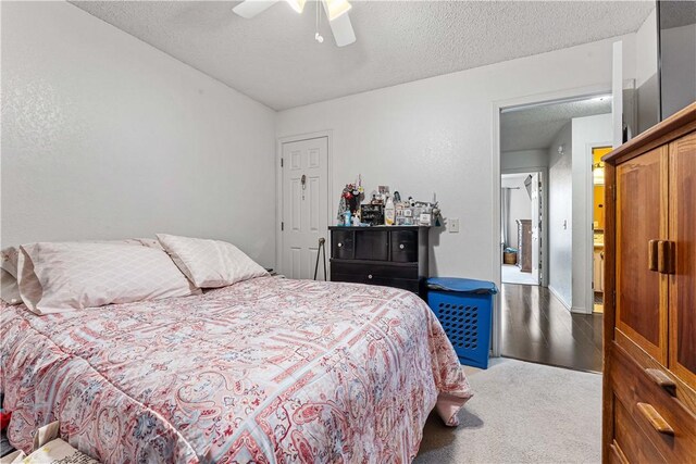 bedroom with ceiling fan, carpet floors, and a textured ceiling