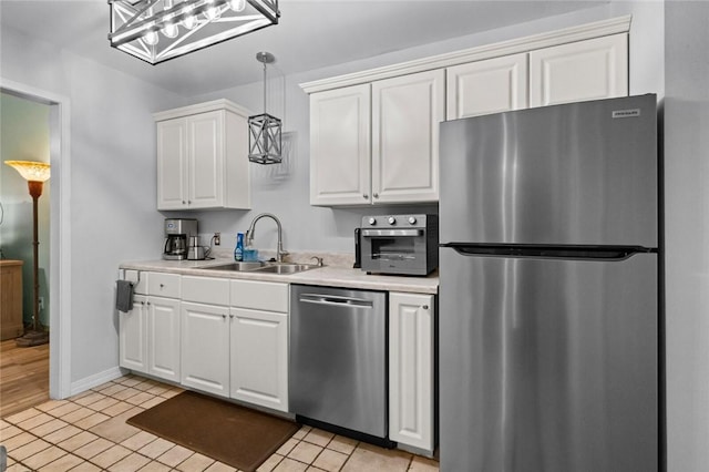 kitchen with light tile patterned flooring, sink, pendant lighting, stainless steel appliances, and white cabinets