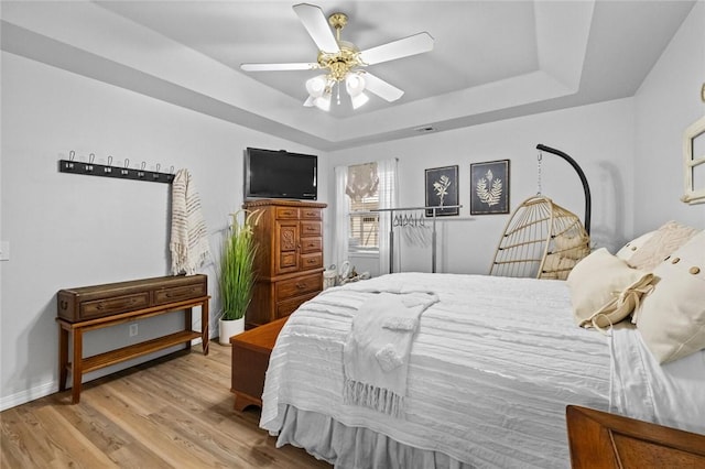 bedroom featuring a tray ceiling, light hardwood / wood-style flooring, and ceiling fan