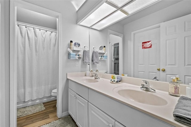 full bathroom featuring toilet, wood-type flooring, a skylight, vanity, and shower / bath combo with shower curtain